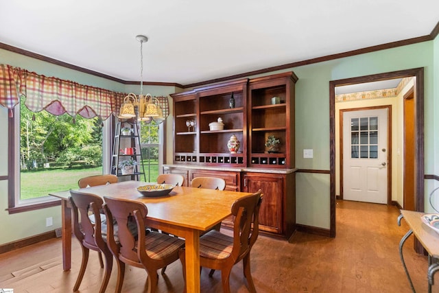 dining space with an inviting chandelier, ornamental molding, light wood-style floors, and baseboards
