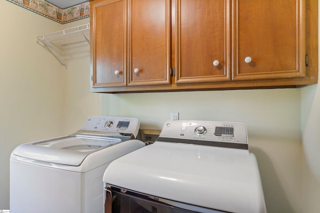 clothes washing area with washing machine and dryer and cabinet space