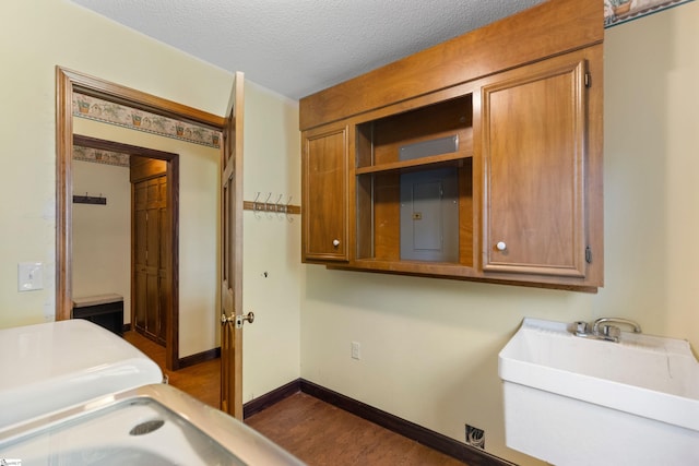 bedroom featuring electric panel, dark wood-style floors, a sink, a textured ceiling, and baseboards