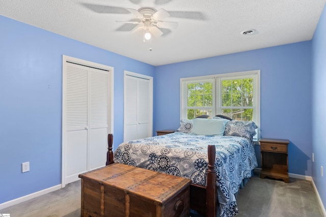 bedroom featuring visible vents, baseboards, carpet, a ceiling fan, and two closets