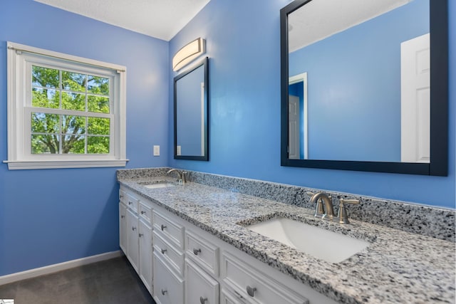 full bath with baseboards, a sink, and double vanity