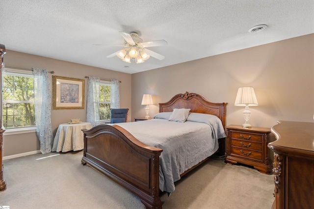 bedroom featuring light carpet, a textured ceiling, visible vents, and baseboards