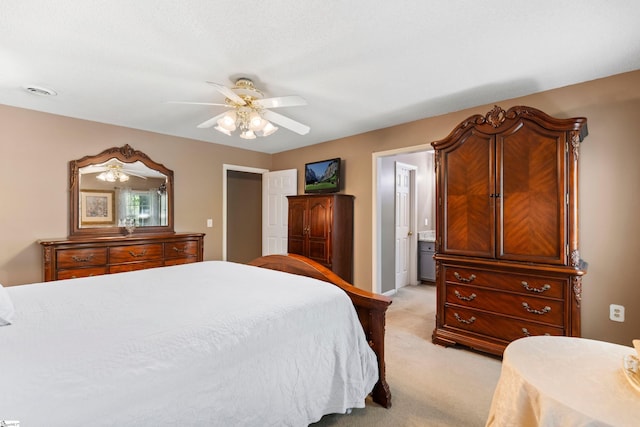bedroom with ensuite bath, a ceiling fan, and light carpet