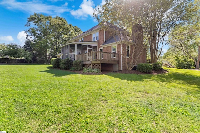 rear view of property featuring brick siding, a sunroom, and a lawn