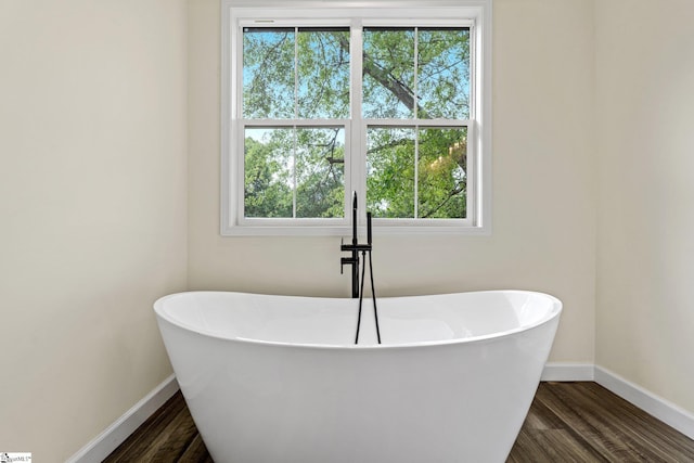 full bath featuring baseboards, a healthy amount of sunlight, and wood finished floors
