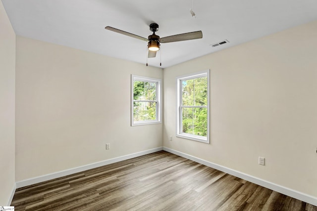 empty room featuring ceiling fan, baseboards, wood finished floors, and visible vents