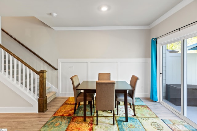 dining area featuring stairway, crown molding, a wainscoted wall, and wood finished floors