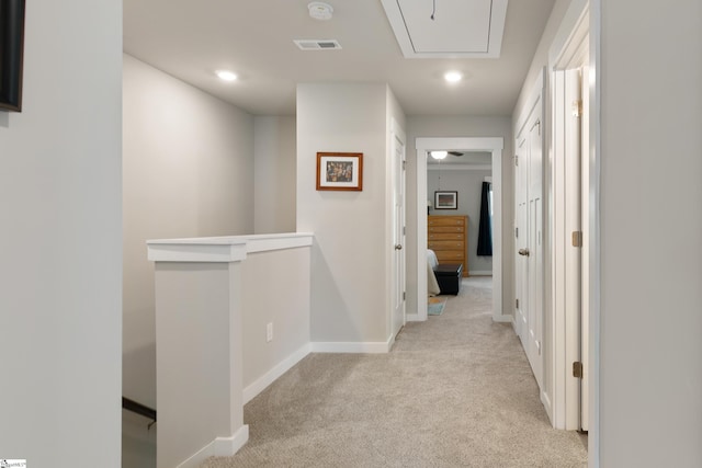 hall with an upstairs landing, attic access, light carpet, visible vents, and recessed lighting