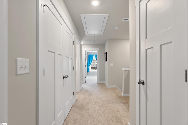hallway featuring attic access, light carpet, visible vents, and baseboards