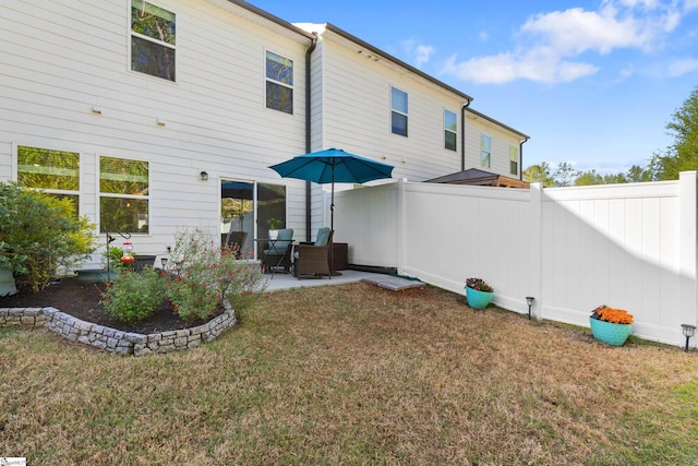 rear view of house with a lawn, fence, and a patio area