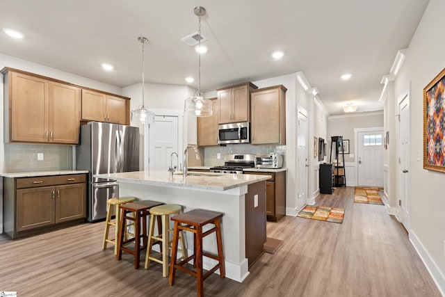 kitchen featuring a kitchen bar, appliances with stainless steel finishes, tasteful backsplash, and a sink