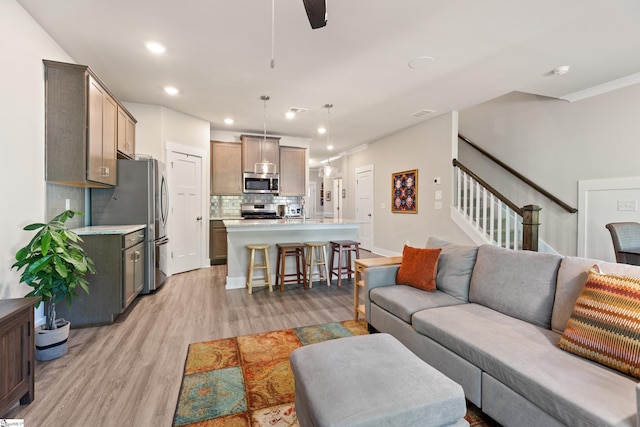 living area with a ceiling fan, stairs, light wood-style flooring, baseboards, and recessed lighting