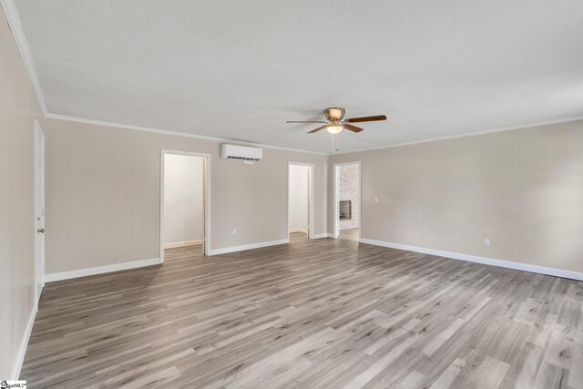 unfurnished room with light wood-style floors, ornamental molding, an AC wall unit, and a ceiling fan