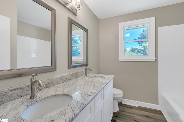 full bath with baseboards, toilet, wood finished floors, and a sink