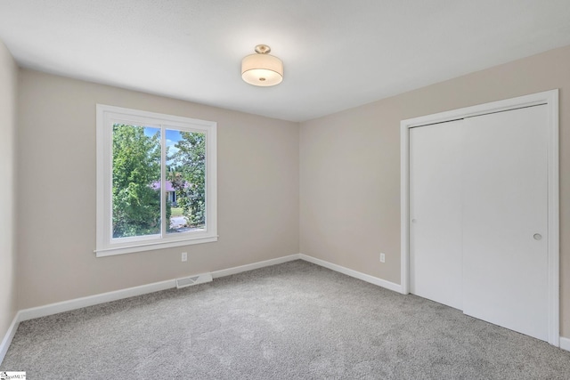 unfurnished bedroom featuring a closet, visible vents, carpet flooring, and baseboards