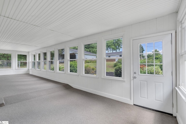 unfurnished sunroom featuring carpet floors and baseboards