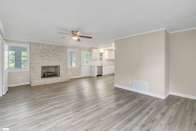 unfurnished living room with visible vents, light wood-type flooring, crown molding, a fireplace, and ceiling fan
