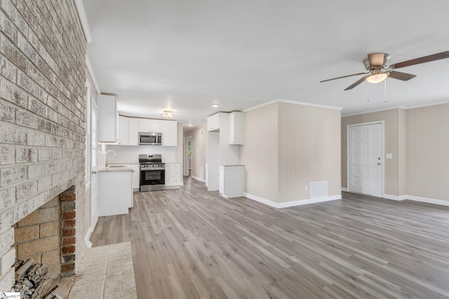 unfurnished living room featuring ornamental molding, a sink, light wood-style floors, a brick fireplace, and ceiling fan