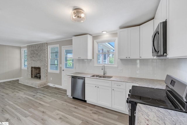 kitchen with crown molding, a sink, stainless steel appliances, white cabinets, and light stone countertops