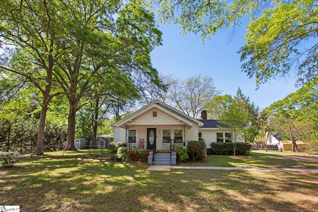 bungalow with a chimney, fence, a porch, and a front yard