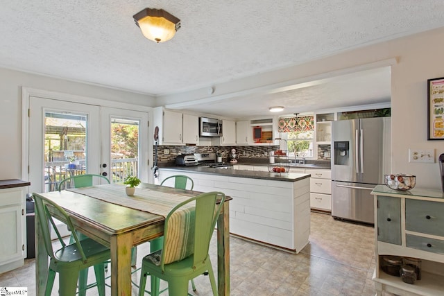 dining area with french doors, a wealth of natural light, and a textured ceiling