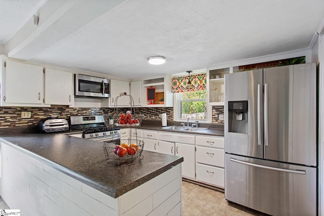 kitchen with open shelves, dark countertops, a sink, a peninsula, and appliances with stainless steel finishes