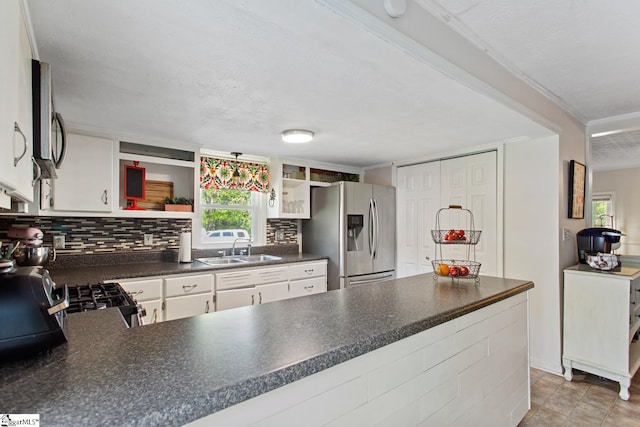 kitchen with a peninsula, a sink, dark countertops, open shelves, and appliances with stainless steel finishes