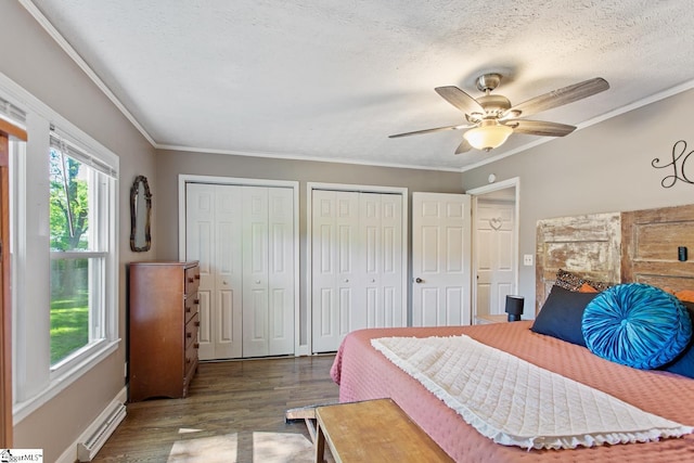 bedroom featuring multiple closets, wood finished floors, ornamental molding, a baseboard radiator, and a textured ceiling