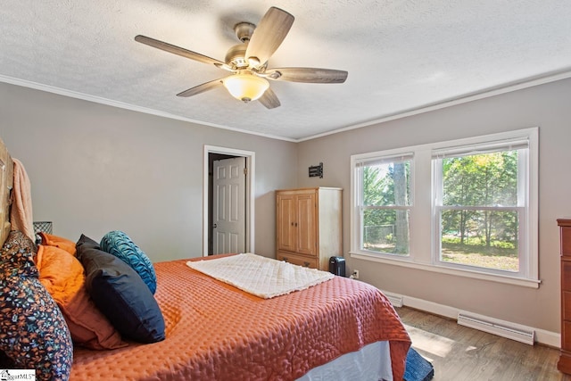 bedroom with baseboards, wood finished floors, a textured ceiling, and ornamental molding