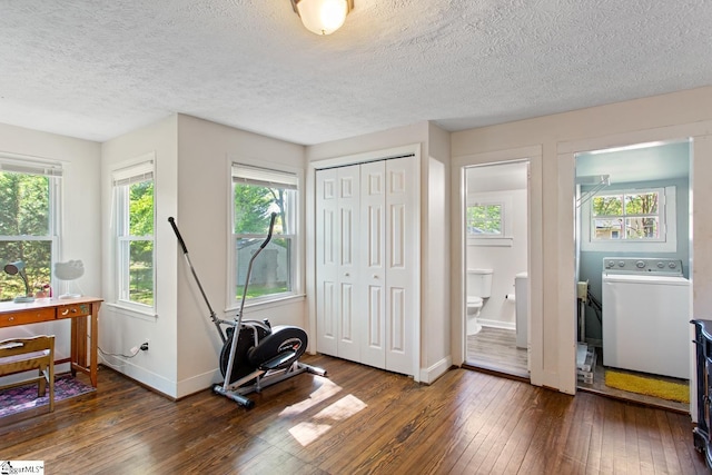 workout area with dark wood-type flooring, a textured ceiling, a wealth of natural light, and washer / clothes dryer