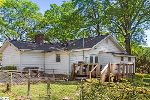 back of house with a chimney, a shingled roof, fence, a yard, and a wooden deck