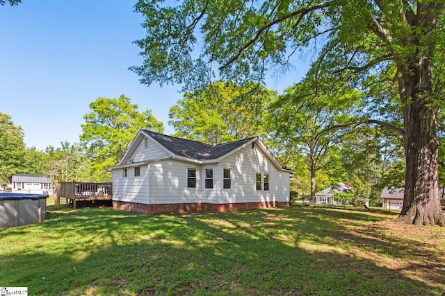 view of home's exterior with a covered pool, a wooden deck, and a yard