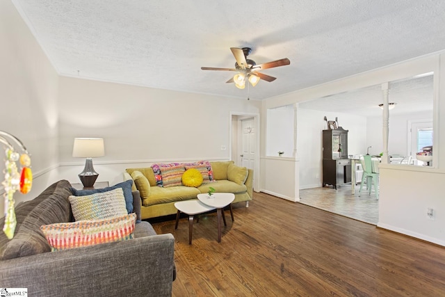 living room featuring wood finished floors, a textured ceiling, a ceiling fan, and baseboards