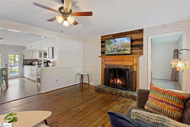 living room with a textured ceiling, visible vents, a brick fireplace, wood finished floors, and ceiling fan