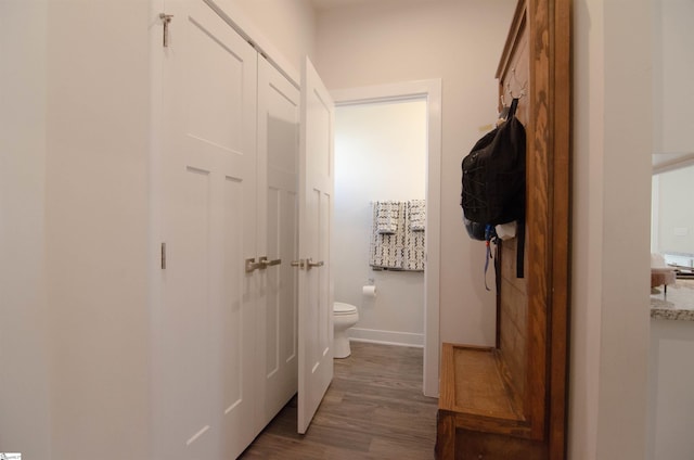 bathroom featuring baseboards, wood finished floors, and toilet