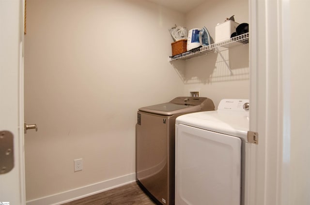 laundry room with washing machine and clothes dryer, dark wood-type flooring, laundry area, and baseboards