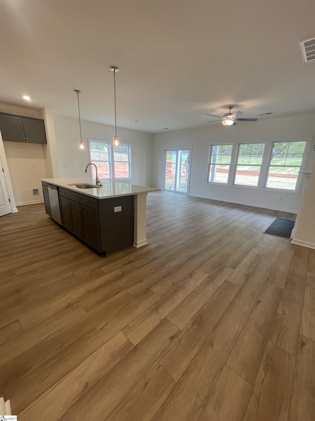 kitchen with stainless steel dishwasher, a sink, open floor plan, visible vents, and wood finished floors