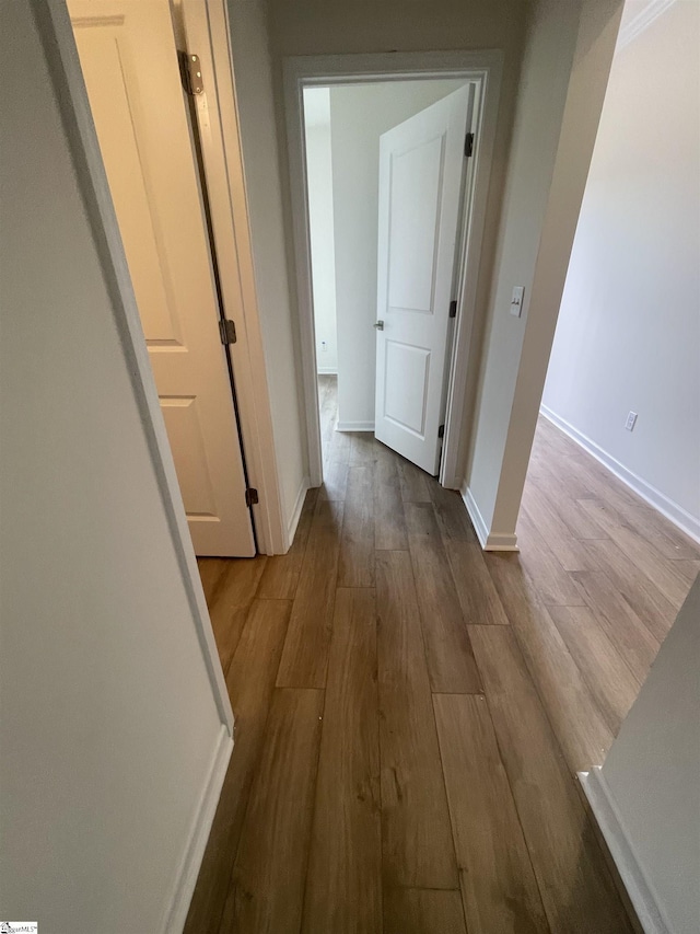 hall featuring baseboards and wood finished floors