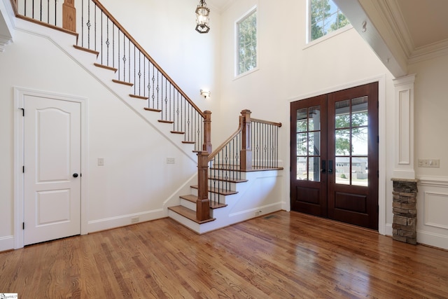 entryway featuring stairway, crown molding, wood finished floors, french doors, and a high ceiling