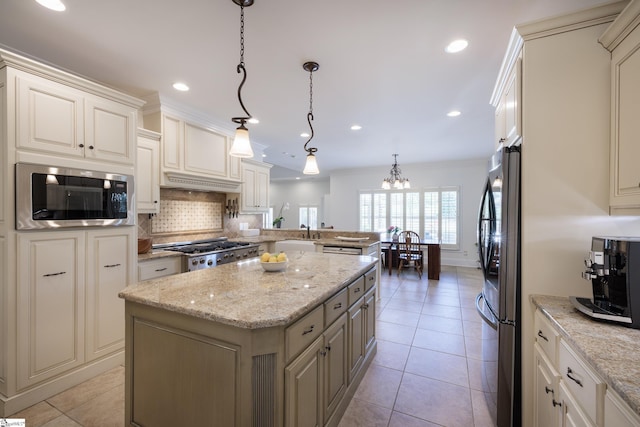 kitchen with a center island, tasteful backsplash, light tile patterned floors, an inviting chandelier, and appliances with stainless steel finishes