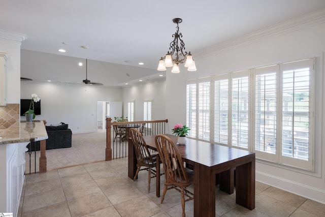 dining room with ceiling fan with notable chandelier, light tile patterned floors, light carpet, baseboards, and ornamental molding