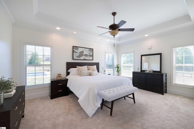 bedroom featuring light colored carpet, a tray ceiling, ornamental molding, and multiple windows