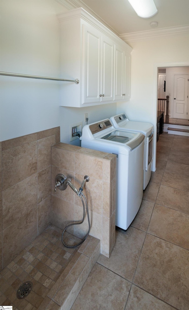 laundry room with washing machine and clothes dryer, light tile patterned flooring, crown molding, and cabinet space