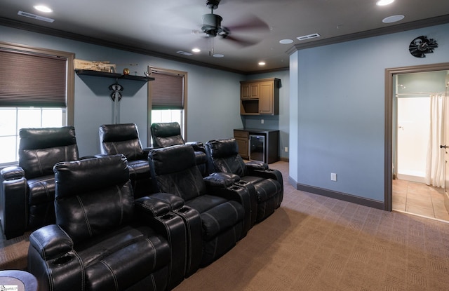 cinema room with light carpet, visible vents, crown molding, and ceiling fan