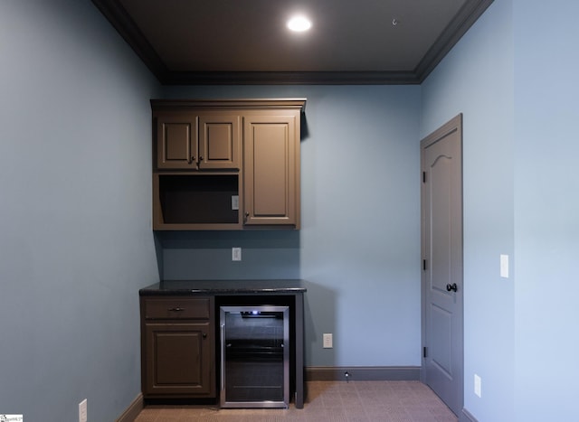bar featuring baseboards, ornamental molding, beverage cooler, and a bar