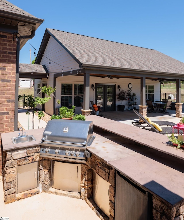 view of patio featuring fence, ceiling fan, a sink, and exterior kitchen