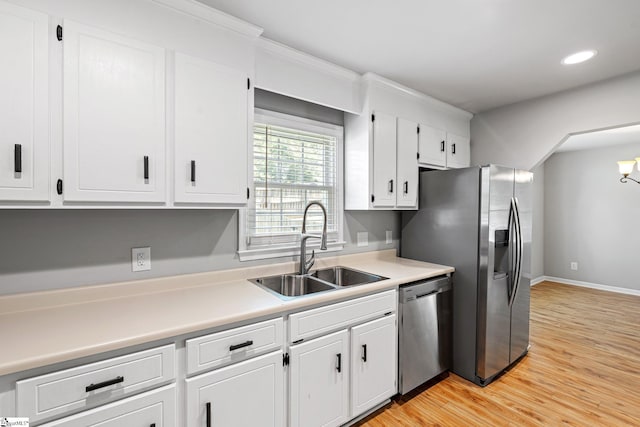 kitchen with a sink, light wood-style floors, white cabinetry, light countertops, and appliances with stainless steel finishes