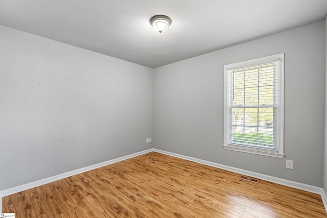 unfurnished room featuring baseboards, wood finished floors, and visible vents