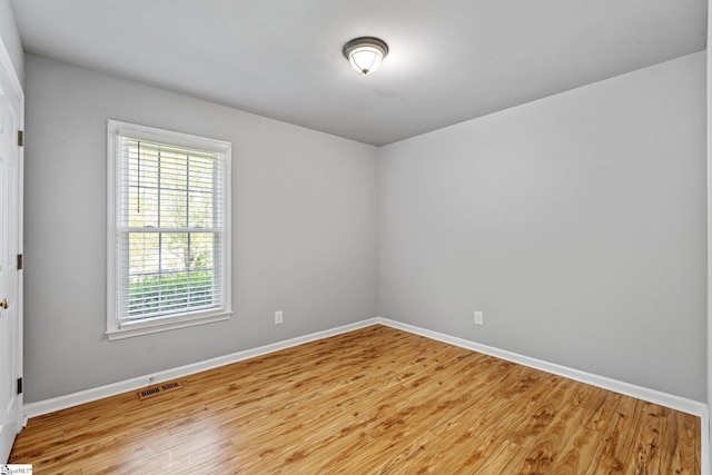 spare room featuring baseboards, light wood-style floors, visible vents, and a wealth of natural light