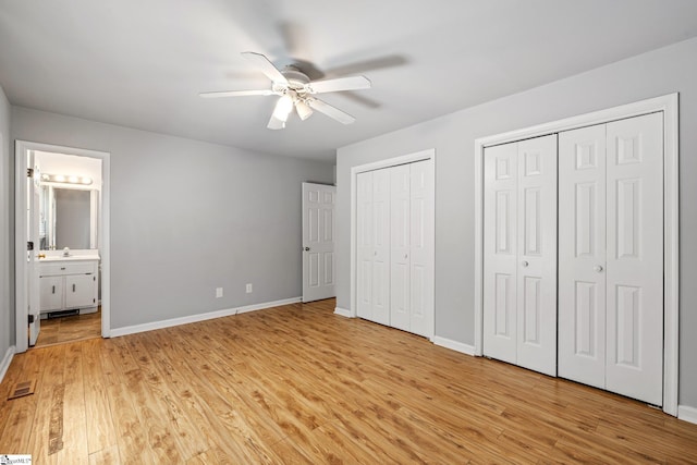 unfurnished bedroom with visible vents, light wood finished floors, baseboards, and multiple closets